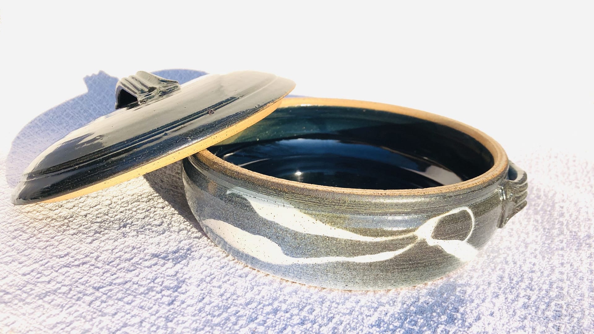 A green and blue casserole dish and lid in blue and turquoise glaze