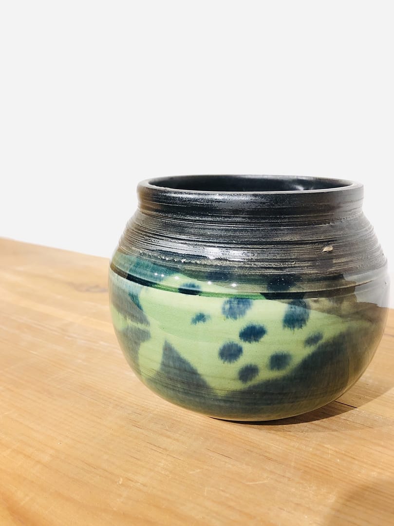 A small, spherical vase glazed with layers of green and blue