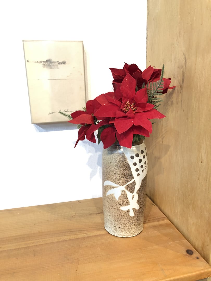 A tall and narrow temmoku brown vase with a floral stencil pattern