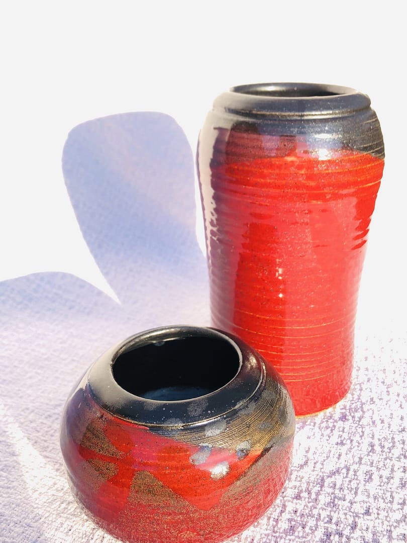 One tall and one short, spherical vase, both in deep firebrick red glaze